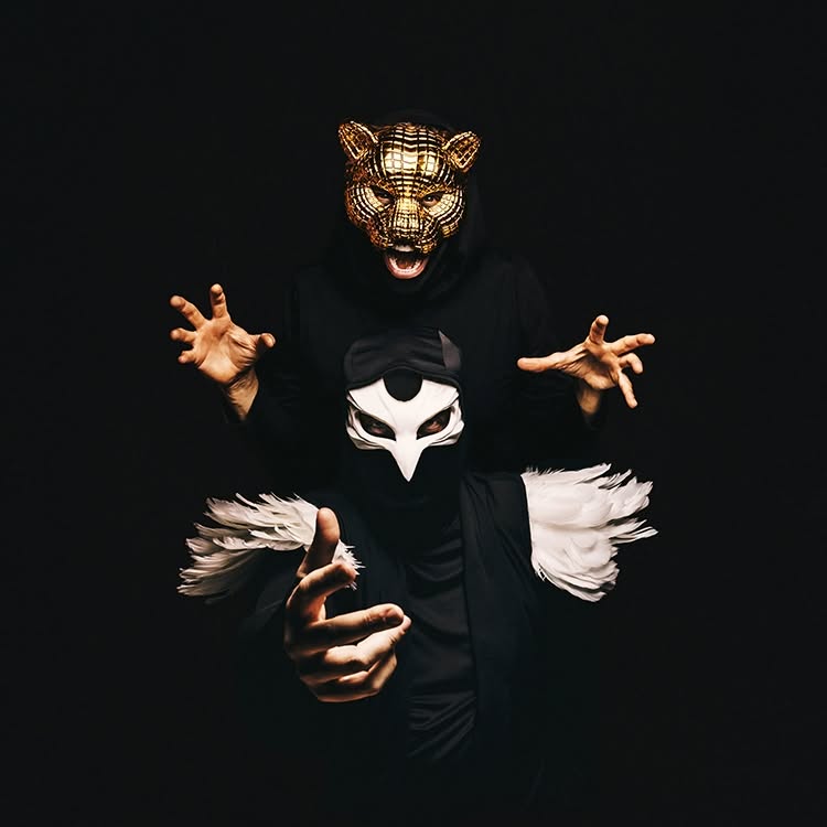 Tiger & Dove in gold tiger and white dove masks, reaching toward the camera